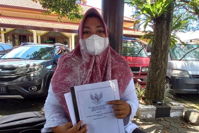 Mantan Bendahara Desa Sumberberas, Kecamatan Muncar, Banyuwangi Gilang Intan Purnama Sari menunjukkan berkas LPJ APBDes 2021 di Polresta Banyuwangi, Senin (4/4/2022).