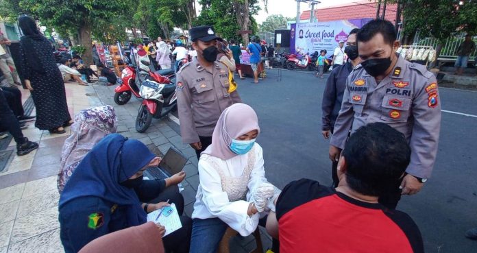 vaksin Pengunjung pasar takjil di Banyuwangi mendapatkan layanan vaksinasi dari Polresta Banyuwangi, Senin (4/4/2022).