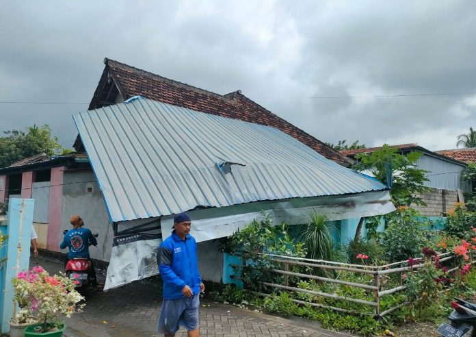 Warga Desa Tampo, Kecamatan Cluring, Banyuwangimembersihkan atap rumah yang jebol akibat terjangan puting beliung, Kamis (15/9/2022) siang.
