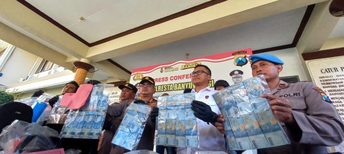 Kapolresta Banyuwangi Kombespol Deddy Foury Millewa menunjukkan barang bukti uang hasil pembobolan ATM, Rabu (7/5/2023). (foto/udi)