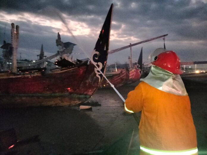 Petugas Damkar memadamkan api yang melalap perahu di dermaga Muncar, Banyuwangi, Senin (11/9/2023) malam. (foto/ist)