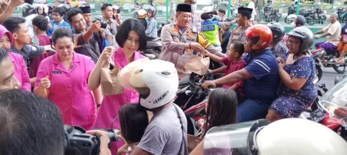Kapolresta Banyuwangi Kombes Pol. Nanang Haryono bersama Ketua Cabang Bhayangkari membagikan takjil ke pengendara motor, Kamis (21/3/2024). (Foto/udi)