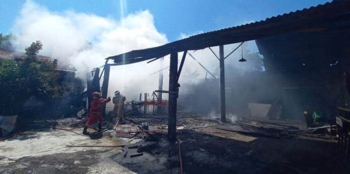 Petugas Damkar menjinakkan api yang membakar garasi rumah di Jalan Brigjen Katamso, Kelurahan Tukangkayu, Kecamatan Banyuwangi, Senin (15/4/2024). (Foto/udi)